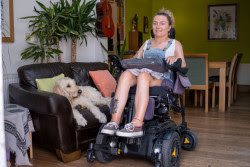 a young girl in a wheelchair with a dog next to her.