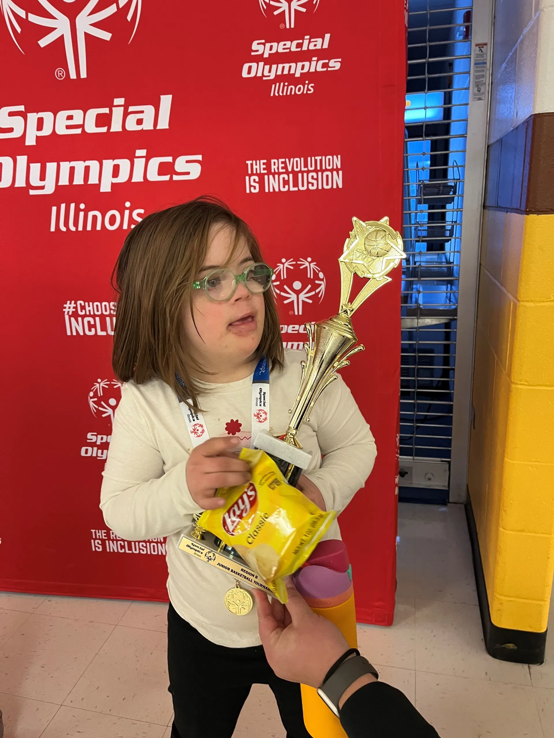 A child with a trophy at the special olympics.