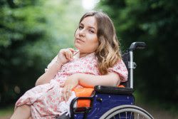 A woman in a wheelchair smiling at the camera.