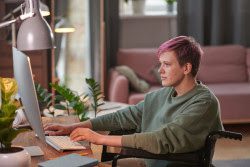 A person typing at a laptop on a desk in their home.