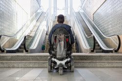 A child in a wheelchair looking up two escalators.