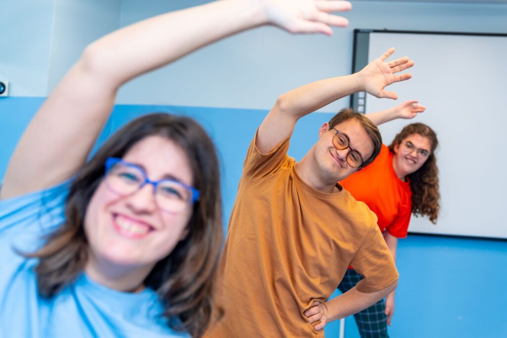 Three young adults with special needs in a gym doing excersizes.